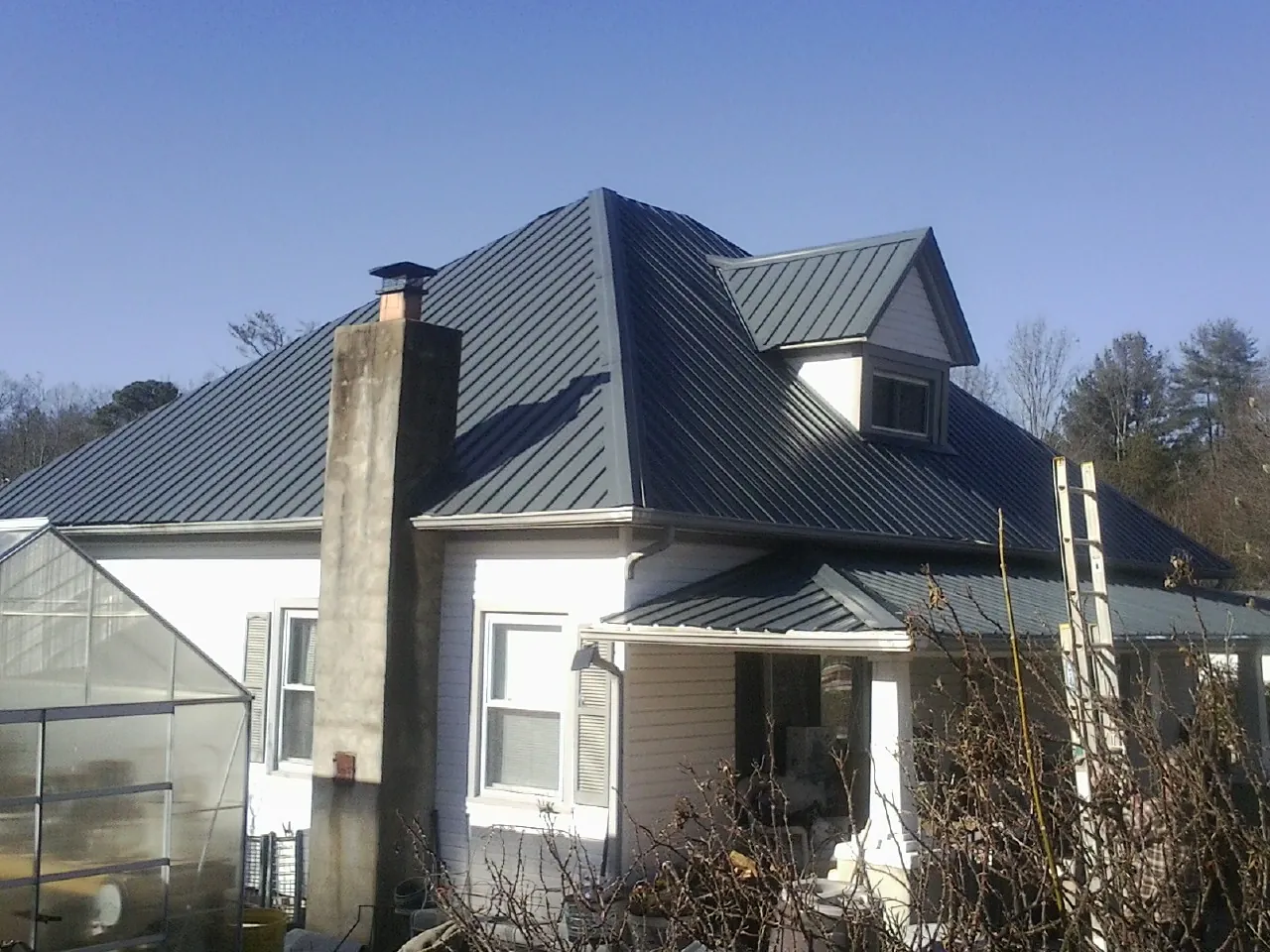 Dark blue standing seam metal roof on a white farmhouse with dormer — Slate & Tile Roof Repair by Roofing Brothers in South Pekin