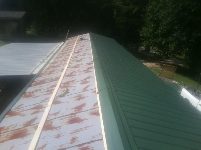 Old rusted panels beside newly installed green metal roofing — Wind Damage Roof Repair by Roofing Brothers in South Pekin