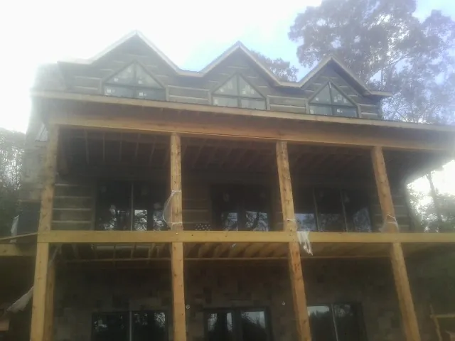 Dormers and porch framing on a large log home under construction — Roof Coating work by our crew in South Pekin