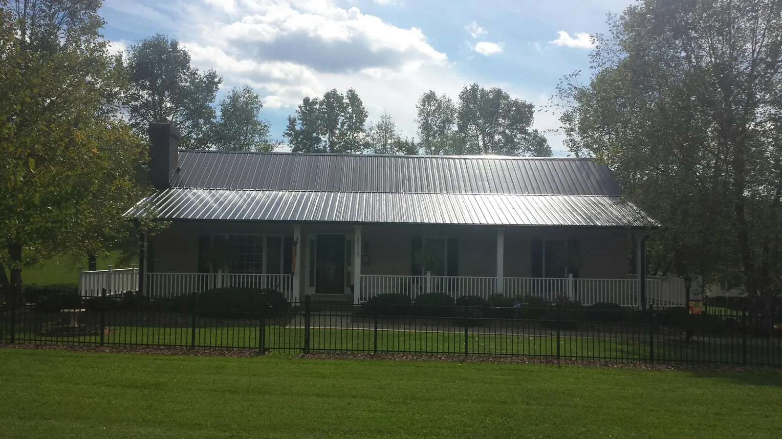 Gray metal roof on a brick ranch with a full width front porch — Gutter Guard Installation work by our crew in South Pekin