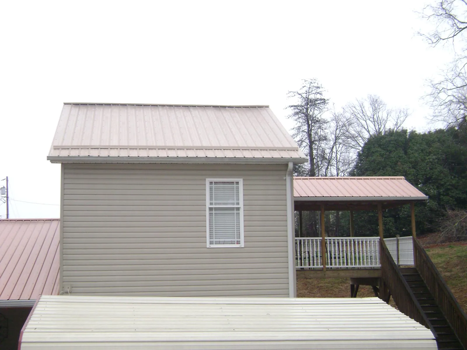 Tan metal roofs on a two story addition and attached porch, from a Roof Replacement job in South Pekin