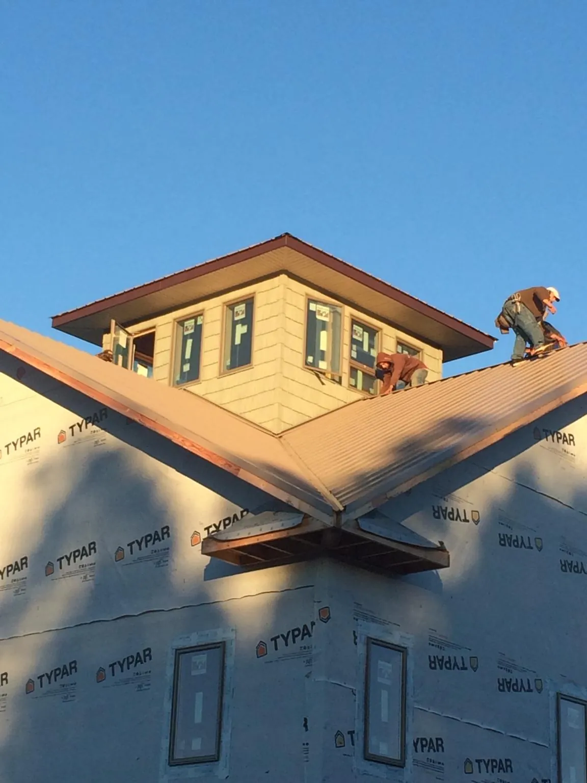 Roofers working around a rooftop cupola on a new metal roof at sunset — Roof Waterproofing in South Pekin by Roofing Brothers